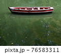 Wooden boat without people with green lake water reflection, row boat side view. 76583311