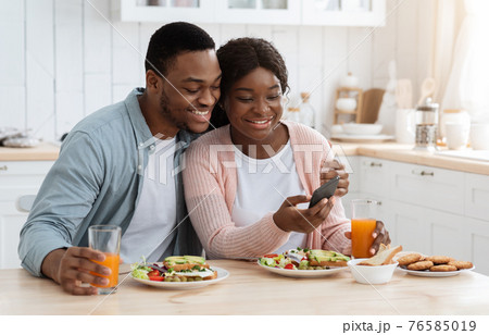 Romantic African American Spouses Checking New App On Smartphone During Breakfast Romantic African American Spouses Checking New App On Smartphone During Breakfast 76585019