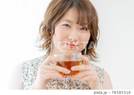 窓辺で紅茶のカップを持つ若い女性 窓辺で紅茶のカップを持つ若い女性 76585310