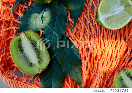 Flat lay of eco friendly mesh shopping bag With Fruits in sunlight, summer time. 76585781