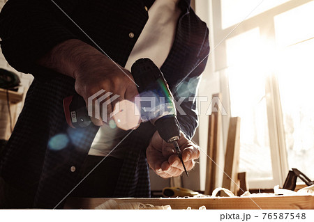 Close up of a carpenter drilling a hole in timber 76587548