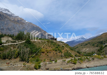 A building under construction on a hill among the mountains with snow-capped peaks near the river A building under construction on a hill among the mountains with snow-capped peaks near the river 76588632