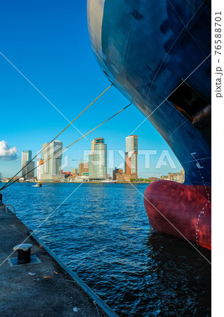 View of Rotterdam skyscrapers skyline from under cargo vessel moored to the quay of Nieuwe Maas river 76588701