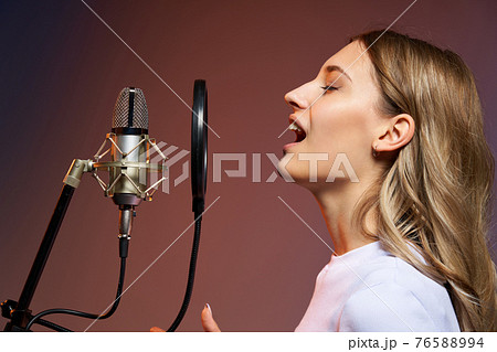 Singer girl with microphone. Closeup profile portrait of young Caucasian girl singing enjoying with closed eyes 76588994
