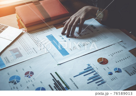 Young business or financial analyst sitting at home office and working on paperwork. Preparing financial report. 76589013