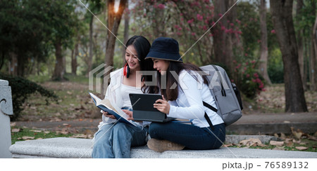 Asian woman traveler with backpack using maps on tablet and sitting in park, travel holiday relaxation concept. Asian woman traveler with backpack using maps on tablet and sitting in park, travel holiday relaxation concept. 76589132