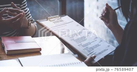 Businesswoman reading resume of man on document during an interview 76589407