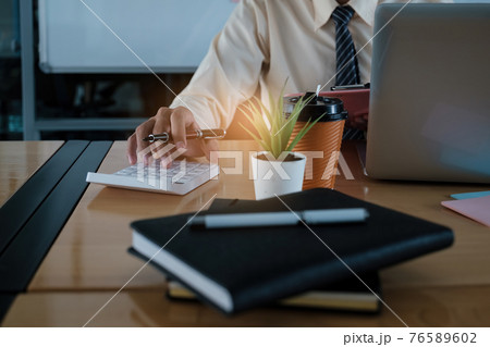Young accountant man analyzes financial data using calculator and laptop computer to compute and summarize big data for present on video conference. financial concept. 76589602