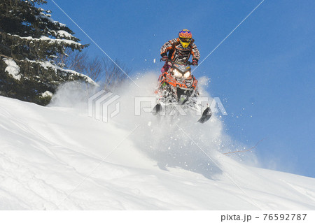 Athlete on a snowmobile moving in the mountains Athlete on a snowmobile moving in the mountains 76592787