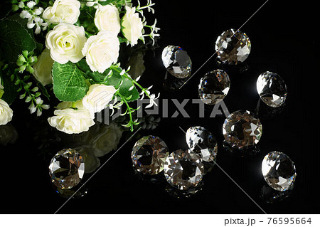 Several excellent pure diamonds and bouquet of white roses with reflection on black mirror background close up view. Jewelry diamonds sale, invitation, action, discount banner, poster template 76595664