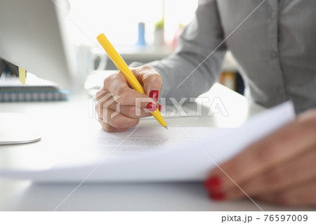 Woman hand holds pen and signs document Woman hand holds pen and signs document 76597009