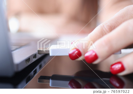Female hand inserts USB flash drive into laptop connector Female hand inserts USB flash drive into laptop connector 76597022