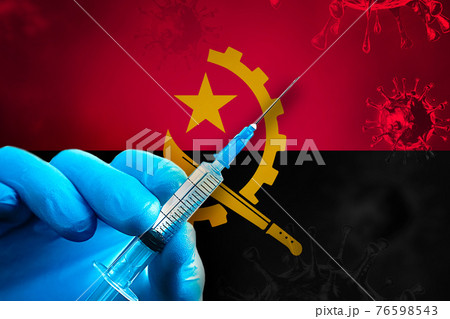 Angola Covid-19 Vaccination Campaign. Hand in a blue rubber glove holds a syringe with covid-19 virus vaccine in front of Angola flag 76598543