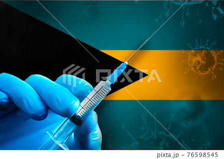 Bahamas Covid-19 Vaccination Campaign. Hand in a blue rubber glove holds a syringe with covid-19 virus vaccine in front of Bahamas flag Bahamas Covid-19 Vaccination Campaign. Hand in a blue rubber glove holds a syringe with covid-19 virus vaccine in front of Bahamas flag 76598545