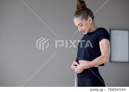 Beautiful fitness model with slim body measures the waist in a fitness club, Healthy nutrition and weight losing concept... 76604544
