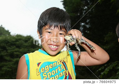 ヒキガエルを捕まえて喜ぶ少年 76604975
