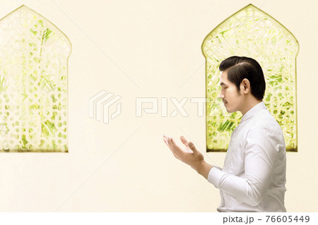Asian Muslim man standing while raised hands and praying Asian Muslim man standing while raised hands and praying 76605449