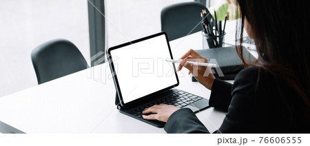 Businesswoman working with a stylus pen on a digital tablet with a laptop computer in a modern office. Businesswoman working with a stylus pen on a digital tablet with a laptop computer in a modern office. 76606555