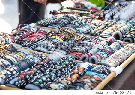 Background with a wide variety of imitation jewelry decorative bracelets, souvenirs, hand made personal beauty accessories sold on a tray in the market 76608229