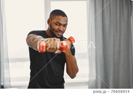 Handsome Afro American sportsman working out at home Handsome Afro American sportsman working out at home 76608954