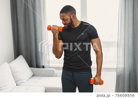 Handsome Afro American sportsman working out at home Handsome Afro American sportsman working out at home 76608956