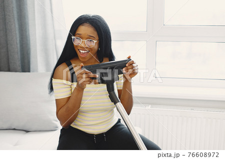 African american woman using vacuum cleaner at home African american woman using vacuum cleaner at home 76608972