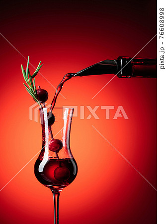 Cranberry liquor is poured from a bottle into a glass. 76608998