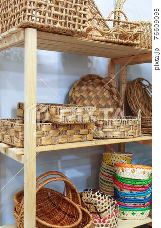 Eco-friendly goods, home space organization and storage, various natural straw wicker baskets stand on a shelf on a wooden rack in a shop window on sale Eco-friendly goods, home space organization and storage, various natural straw wicker baskets stand on a shelf on a wooden rack in a shop window on sale 76609093