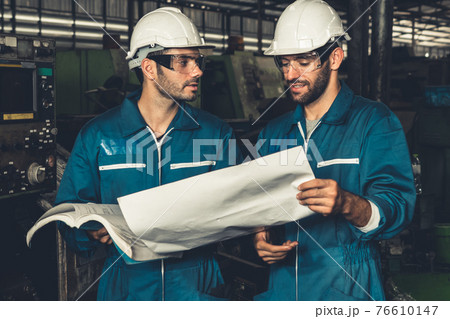 Group of skillful factory workers using machine equipment in workshop 76610147