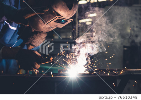 Skillful metal worker working with arc welding machine in factory 76610348