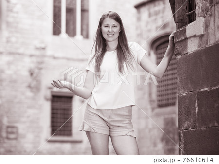 Young woman standing near old stone wall Young woman standing near old stone wall 76610614