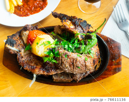 Baked veal chop with side dish of potatoes and vegetables Baked veal chop with side dish of potatoes and vegetables 76611136