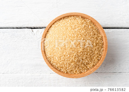 Brown cane sugar in bowl on rustic wooden table. Top view Brown cane sugar in bowl on rustic wooden table. Top view 76613582