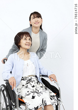 シニア女性の乗った車椅子を押す女性 シニア女性の乗った車椅子を押す女性 76614716