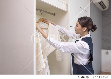 Smiling maid with White bathrobe with hanger in wardrobe, The concept of the hotel business Smiling maid with White bathrobe with hanger in wardrobe, The concept of the hotel business 76615398