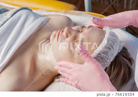 Professional beautician makes a facial massage to 76619384