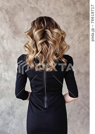Beautiful woman back with curly hairdo on gray background 76619717