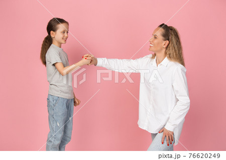 Young woman and girl, mother and daughter isolated over pink background. Young woman and girl, mother and daughter isolated over pink background. 76620249