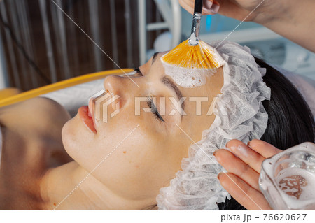 Professional beautician woman applies mask with 76620627
