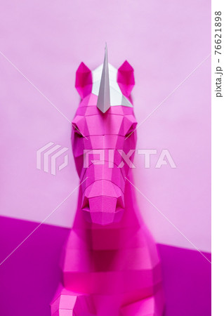 Head of a unicorn of paper on a pink and blue background. 76621898