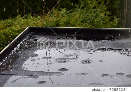 Light rain on a black flat roof against a green background Light rain on a black flat roof against a green background 76625284