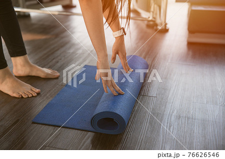 Healthy woman rolling preparing yoga mat for fitness class 76626546