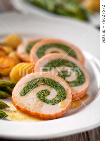 Turkey breast stuffed with roasted potatoes and asparagus. 76627572