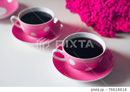 Two pink coffee cups on white background, coffee break and caffeine addiction concept. yellow flowers on the table 76628618
