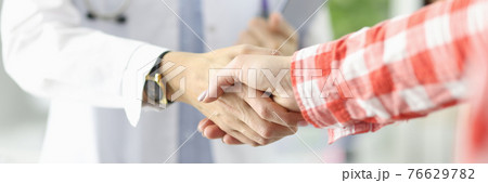 Doctor holding documents and shaking hands with patient in clinic close-up Doctor holding documents and shaking hands with patient in clinic close-up 76629782