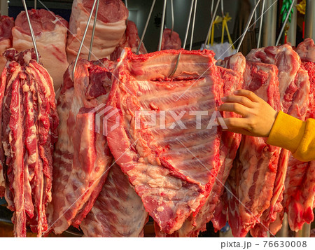 People choosing pork ribs at butcher's market People choosing pork ribs at butcher's market 76630008