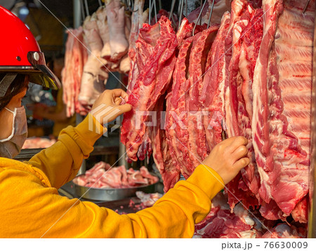 Vietnamese woman buying pork spare ribs at meat market Vietnamese woman buying pork spare ribs at meat market 76630009