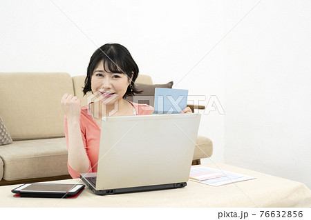 パソコンを見ながら預金通帳を持ってポーズをとる若い女性 パソコンを見ながら預金通帳を持ってポーズをとる若い女性 76632856