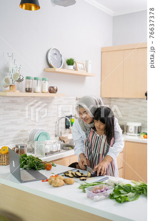 muslim asian woman with her daughter cooking together in the kitchen during ramadan muslim asian woman with her daughter cooking together in the kitchen during ramadan 76637378