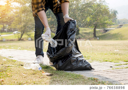 Man's hands pick up plastic bottles, put garbage in black garbage bags to clean up at parks, avoid pollution, be friendly to the environment and ecosystem Man's hands pick up plastic bottles, put garbage in black garbage bags to clean up at parks, avoid pollution, be friendly to the environment and ecosystem 76638898